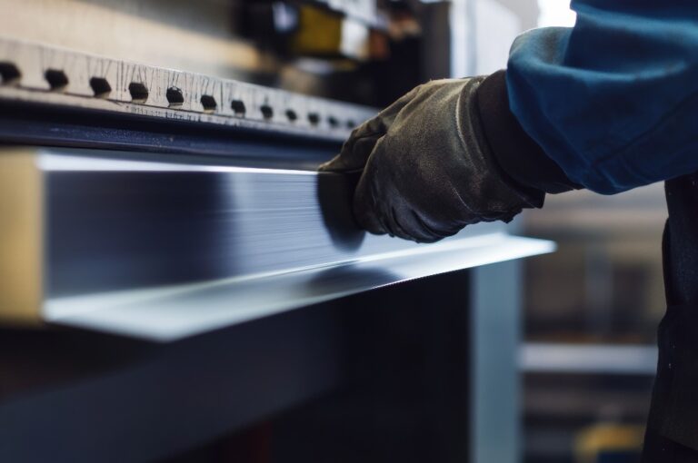 Ein Blechbearbeiter biegt Stahlbleche in einer Werkstatt. Er zeichnet sich durch Geschicklichkeit und Präzision aus.