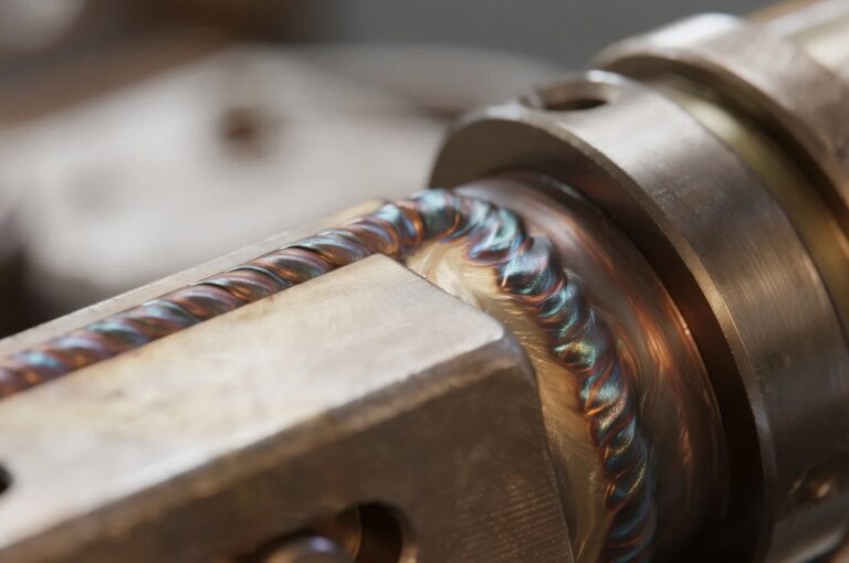Nahaufnahme eines Metallwerkstücks während des Schweißvorgangs mit sichtbarer Wärmeeinflusszone